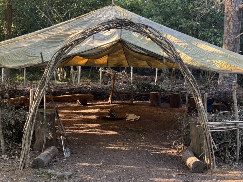 A woven hazel arch leading into the woodland gathering circle